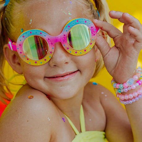 Close-up of a child wearing Googles Flower Bud with round frames and pink ombre floral design for kids ages 6 and up.