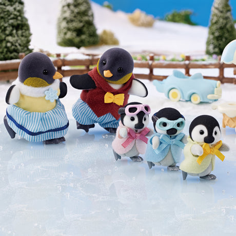 Penguin Family toy set with dressed flocked penguins ice skating on icy surface with snowy background and trees.