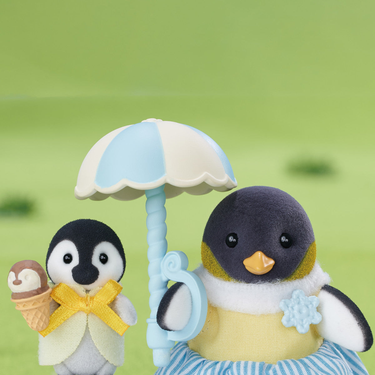 Penguin Family featuring flocked mother and baby penguins with ice cream and umbrella accessories on green background.