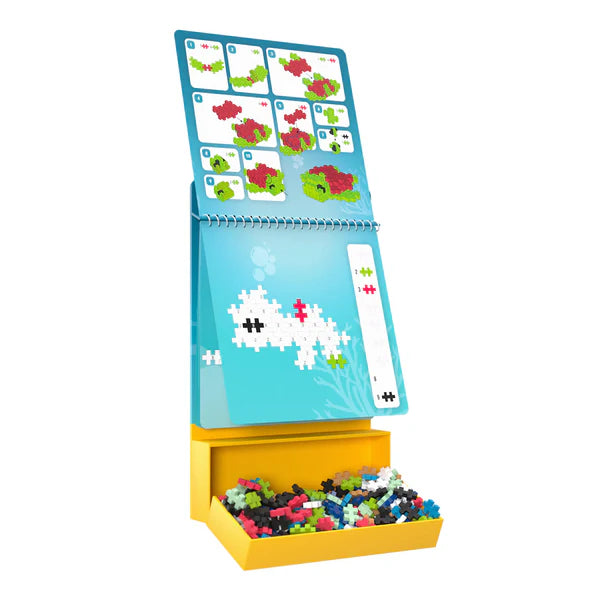 Plus Plus Activity Pad | Ocean showing ocean-themed 2D building instructions and colorful pieces in storage box.