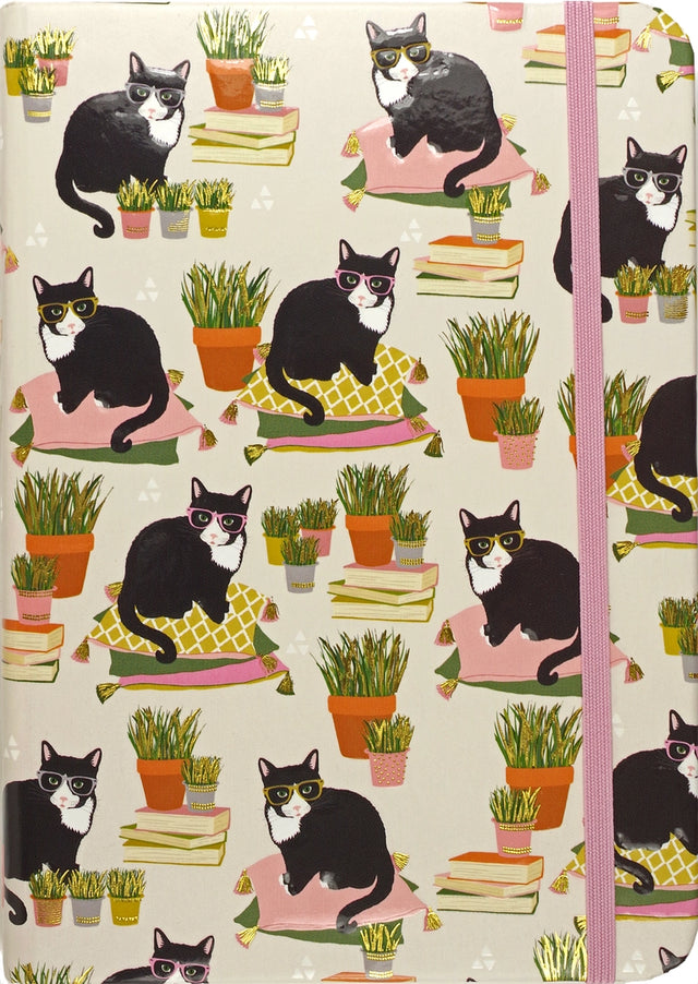 Journal cover with black and white cats wearing glasses sitting on colorful pillows among potted plants and books