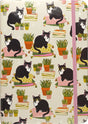 Journal cover with black and white cats wearing glasses sitting on colorful pillows among potted plants and books