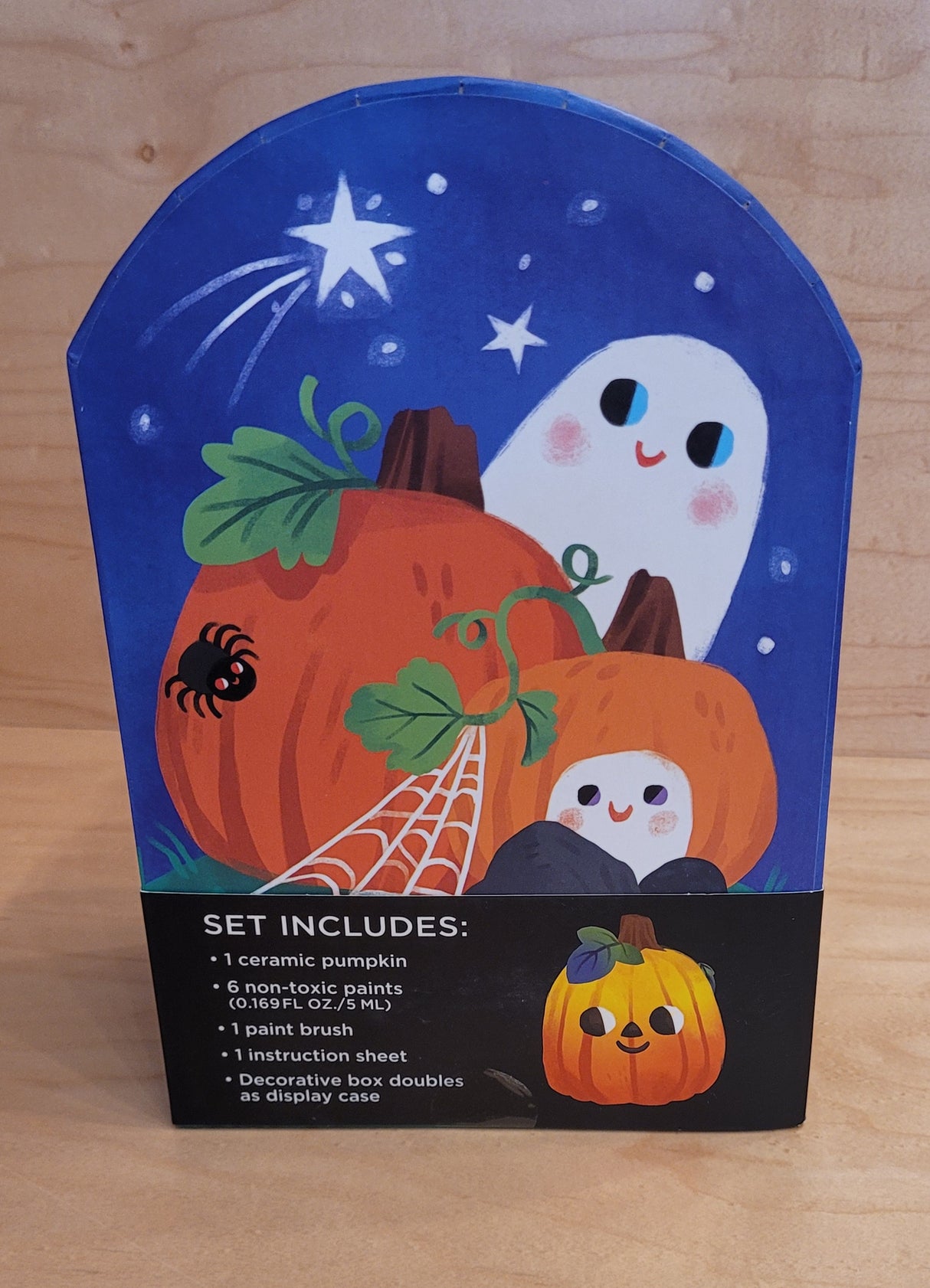 Colorful packaging featuring pumpkins, a smiling ghost, and a spider with product details on a wooden surface
