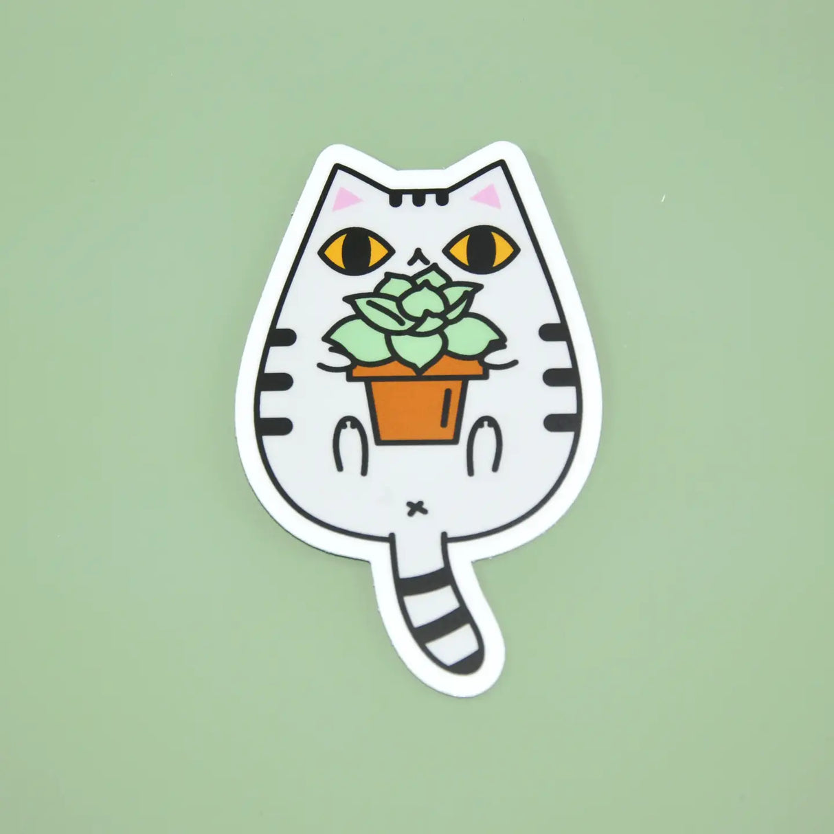Gray Tabby Cat and Plant Sticker featuring a cute white tabby cat holding a potted green succulent plant on a green background.