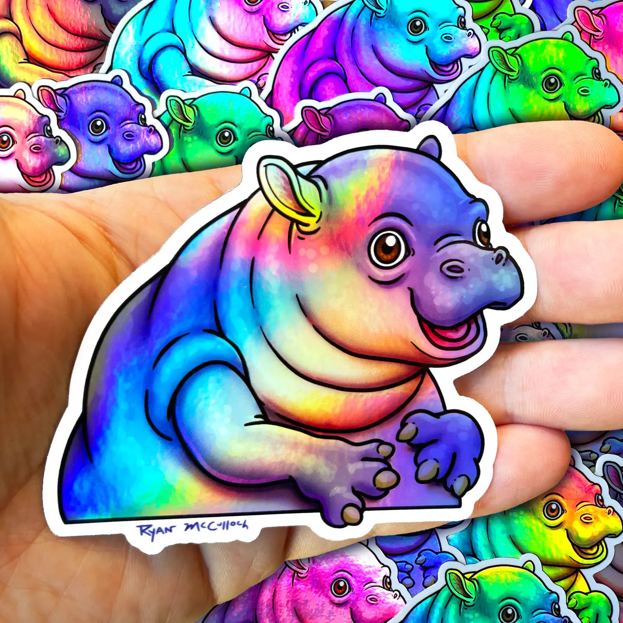 Pygmy Hippo Holographic Sticker showing a colorful, waterproof, durable design by Ryan McCulloch held in hand.