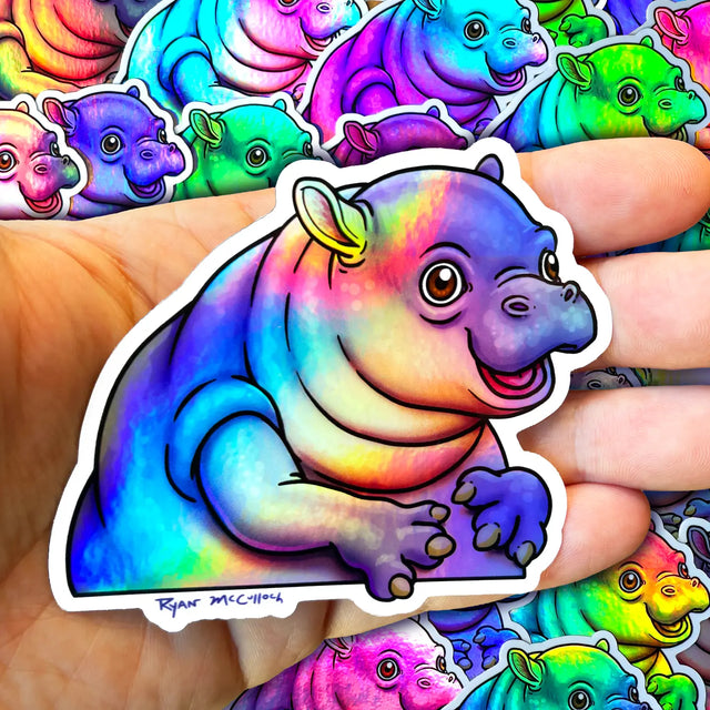 Pygmy Hippo Holographic Sticker showing a colorful, waterproof, durable design by Ryan McCulloch held in hand.