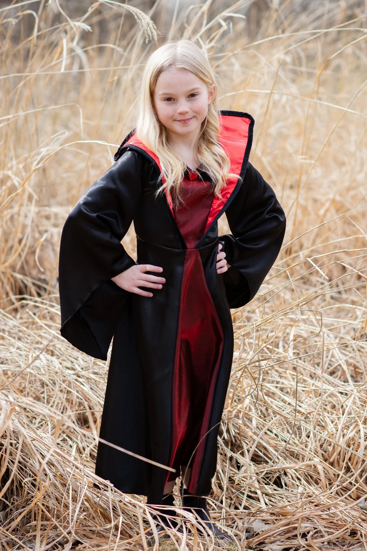 Young girl wearing Vampire Dress | Size 5-6 with black cloak and red interior standing outdoors in tall grass.
