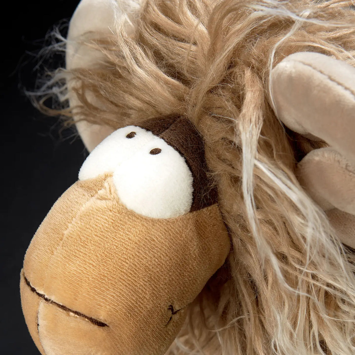 Close-up of plush toy face with fluffy hair and large eyes, showcasing the Mufflon Muff product for children 12+.