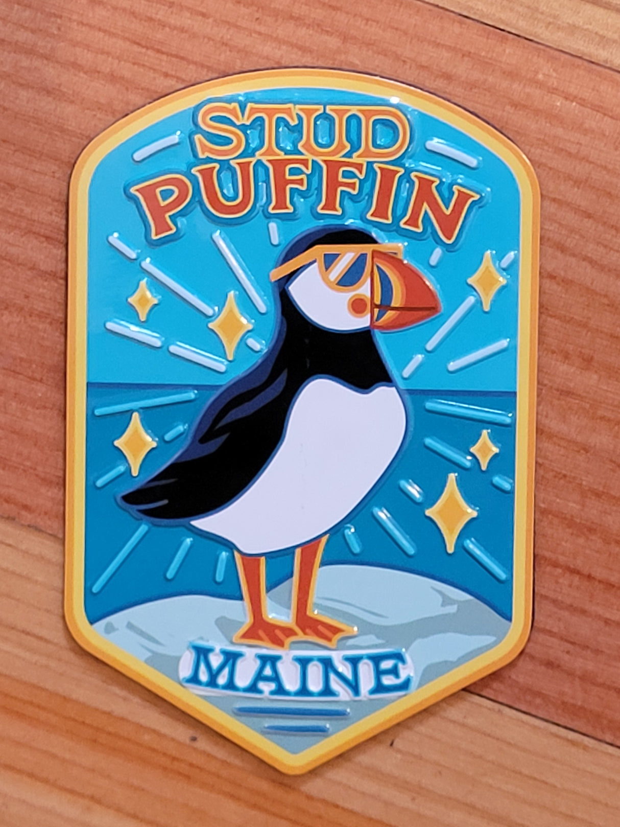 Maine Stud Puffin Magnet featuring a quirky puffin with sunglasses on a blue ocean background, perfect for fridge decor.