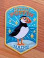 Maine Stud Puffin Magnet featuring a quirky puffin with sunglasses on a blue ocean background, perfect for fridge decor.