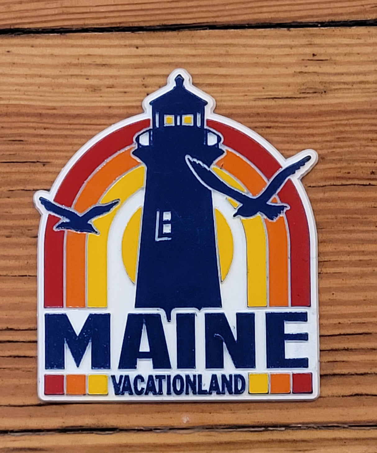 Maine Retro Lighthouse Magnet with vintage lighthouse, colorful sunset, and seagulls design on wood background.
