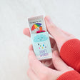 Hands holding Don't Worry Doll Matchbox with a small worry doll and comforting message inside a pastel rain cloud design.
