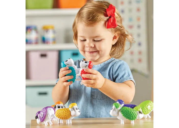Toddler playing with colorful Snap-n-Learn Counting Sheep educational toys in a bright learning space.