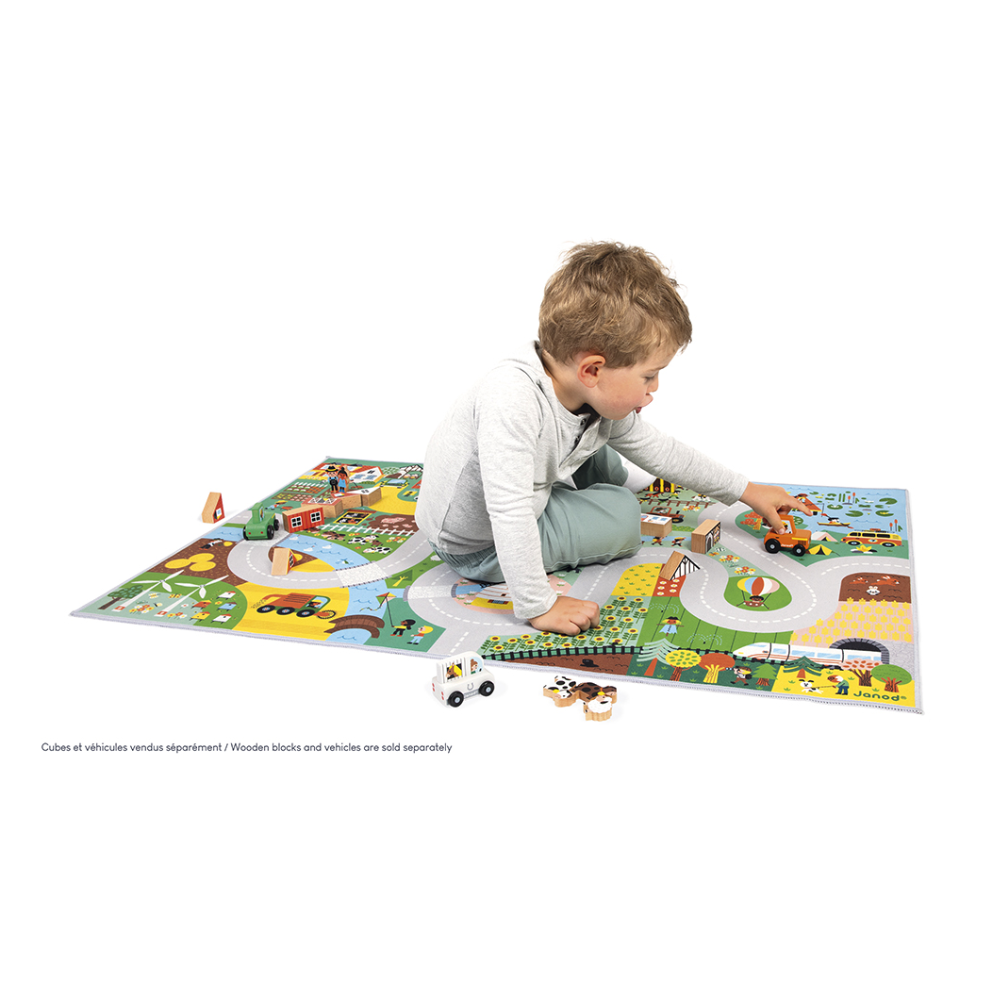 Child playing on Crossroads Countryside Play Mat featuring roads, farm, forest, animals, and buildings for imaginative play.