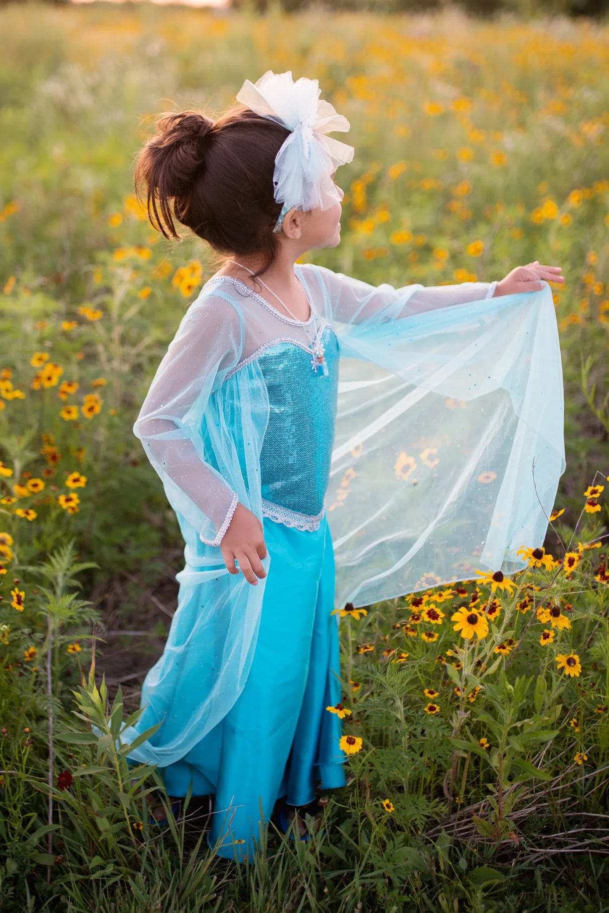 Young girl wearing the Ice Queen Dress with Cape Size 5-6 in blue with sparkle tulle cape outdoors.
