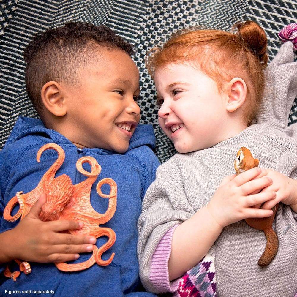 Two children smiling and holding a Giant Pacific Octopus toy, showing its detailed arms and suction cups.