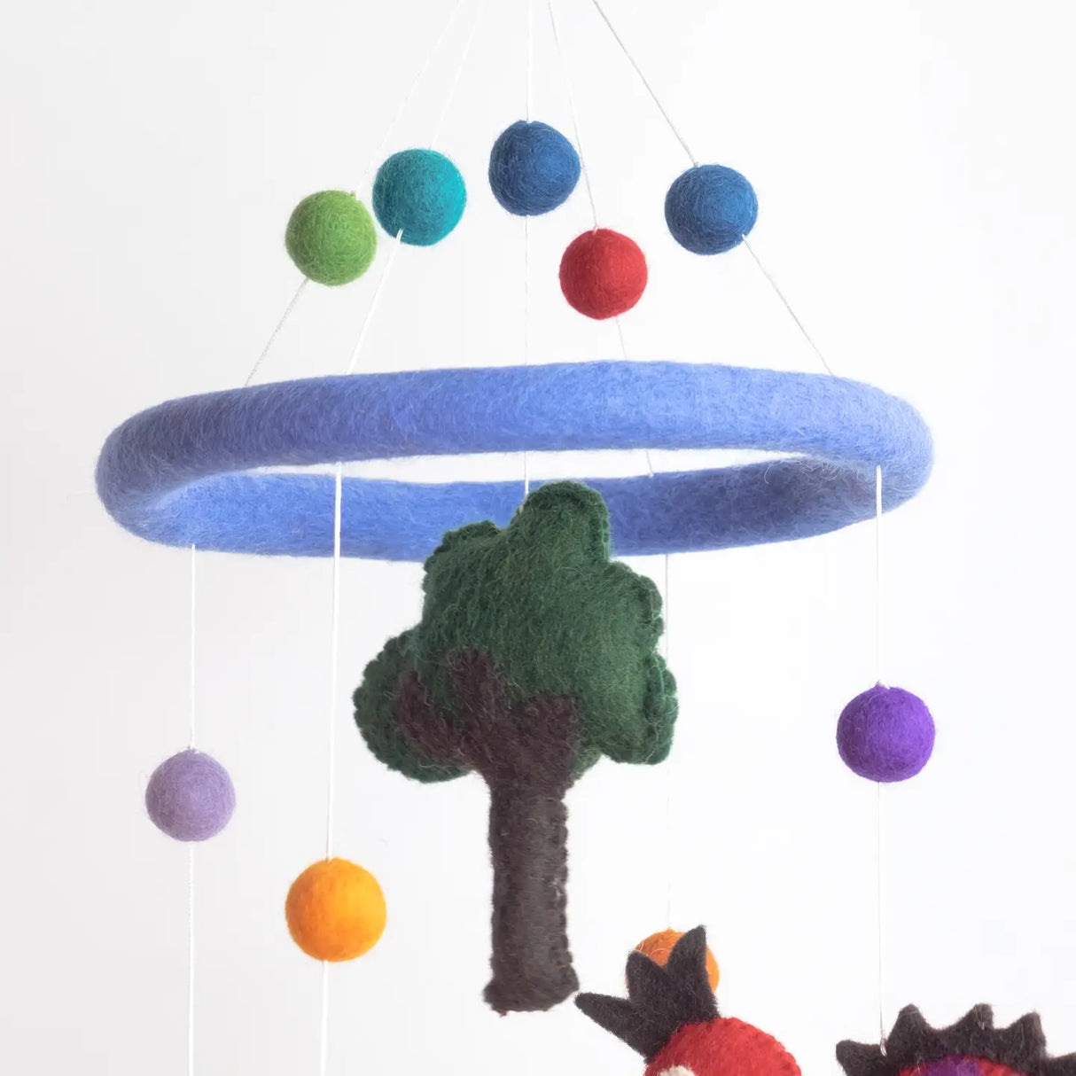 Felt Mobile | Dinosaur with colorful felt balls and tree hanging from a soft blue wool ring mobile.