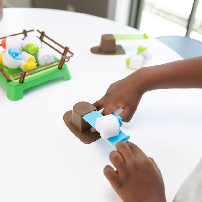 Child playing the Heap-O-Sheep game using a springboard to launch hook-and-loop sheep onto the paddock.