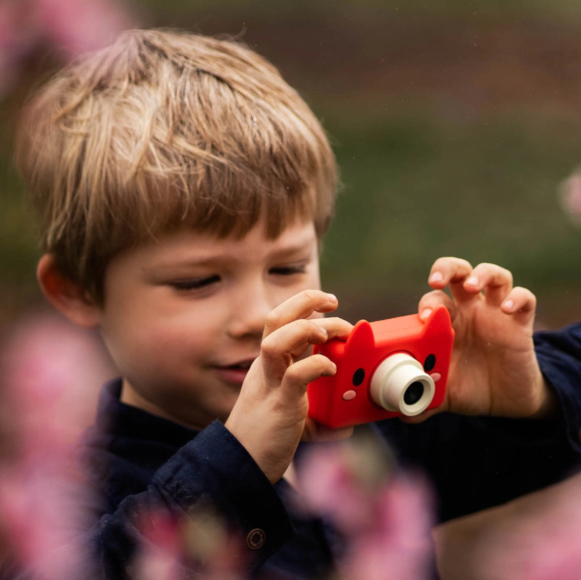 Child holding and using the Digital Camera Model C | Akito the Fox with a red silicone case outdoors.
