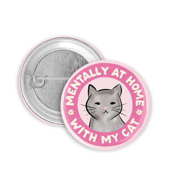 Button Mentally At Home With My Cat shows a gray cat illustration on a pink 1.25 inch round pin badge.