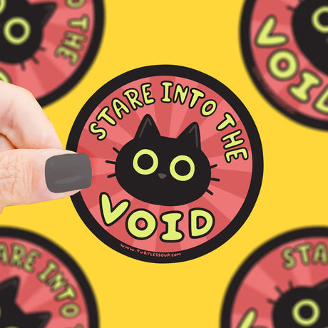Hand holding Stare Into the Void Sticker featuring a black cat on red background, durable vinyl, weatherproof design.