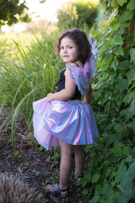 Young girl wearing Magical Unicorn Skirt & Wings with shiny iridescent fabric and glittery bluish purple tulle wings outdoors.