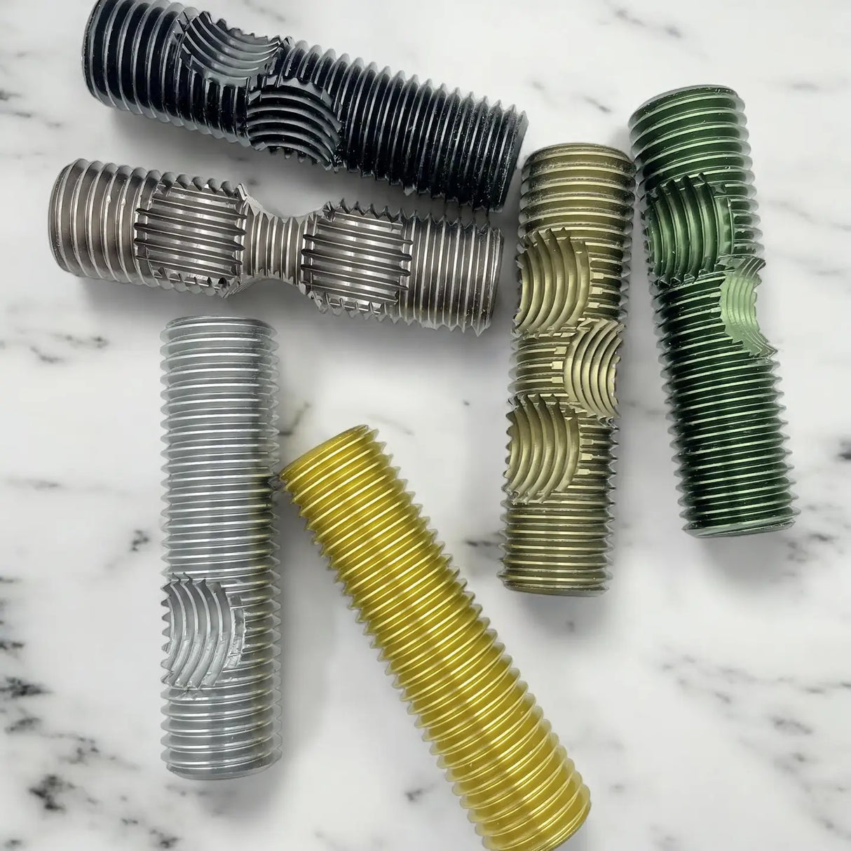 Six interlocked metal bolts in various colors arranged on a marble surface, challenging brainteaser puzzle pieces.
