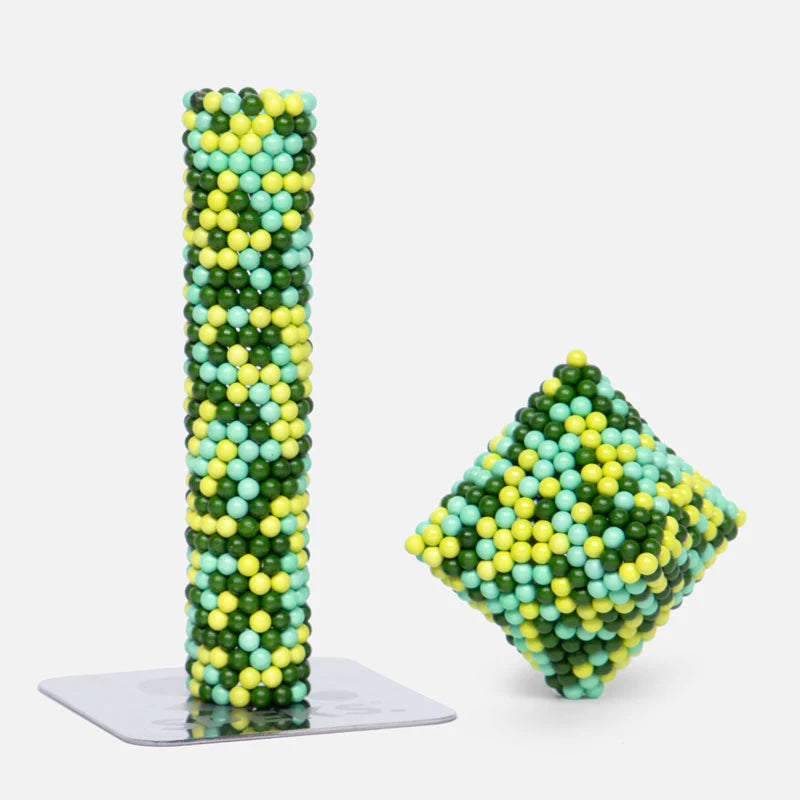 Speks. Pixel. Motherboard. magnetic balls shaped into a tall cylinder and tilted cube with green, yellow, and blue colors.