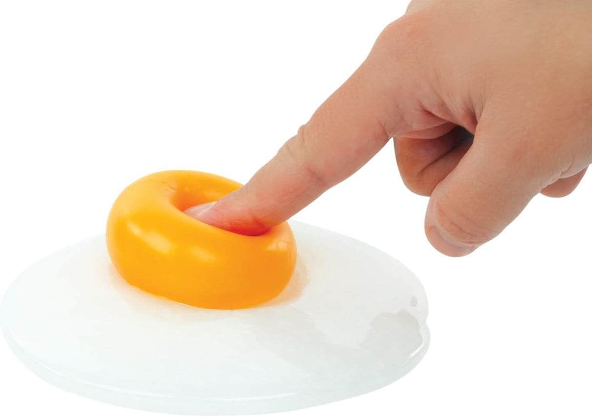 Finger pressing the yellow globby ball of Egg-cellent Thinking Putty on a white surface for fidget play.