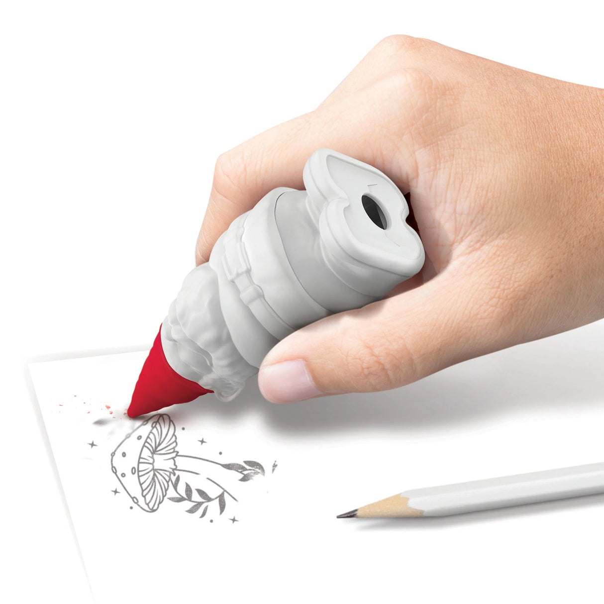 Hand holding a red Desk Gnome eraser with built-in sharpener drawing on paper beside a pencil.