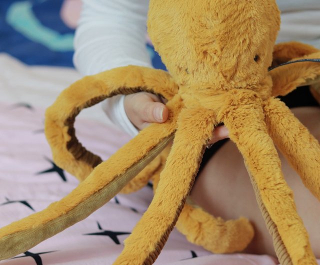 Child holding a large soft velvet octopus plush with detailed tentacles from Moulin Roty, perfect for toddlers.