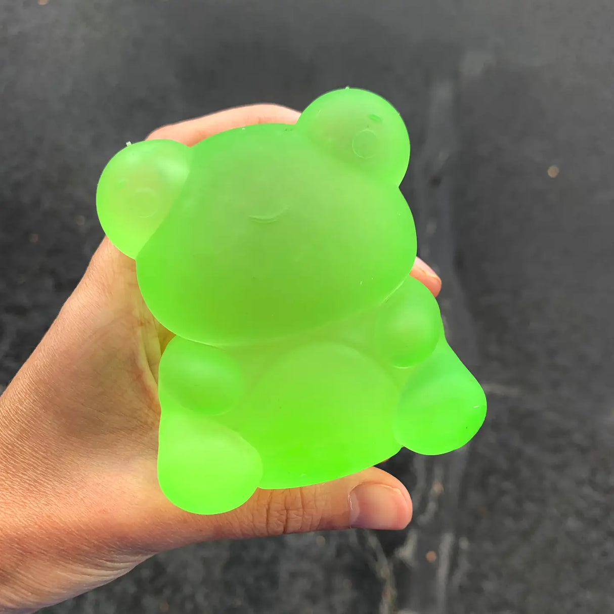 Hand holding a bright green Super Duper Sugar Squisher Frog with a soft, squishy texture for hours of fun.