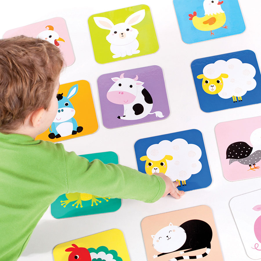 Child playing with colorful animal cards from the Suuuper Size Memory Game featuring farmhouse friends.