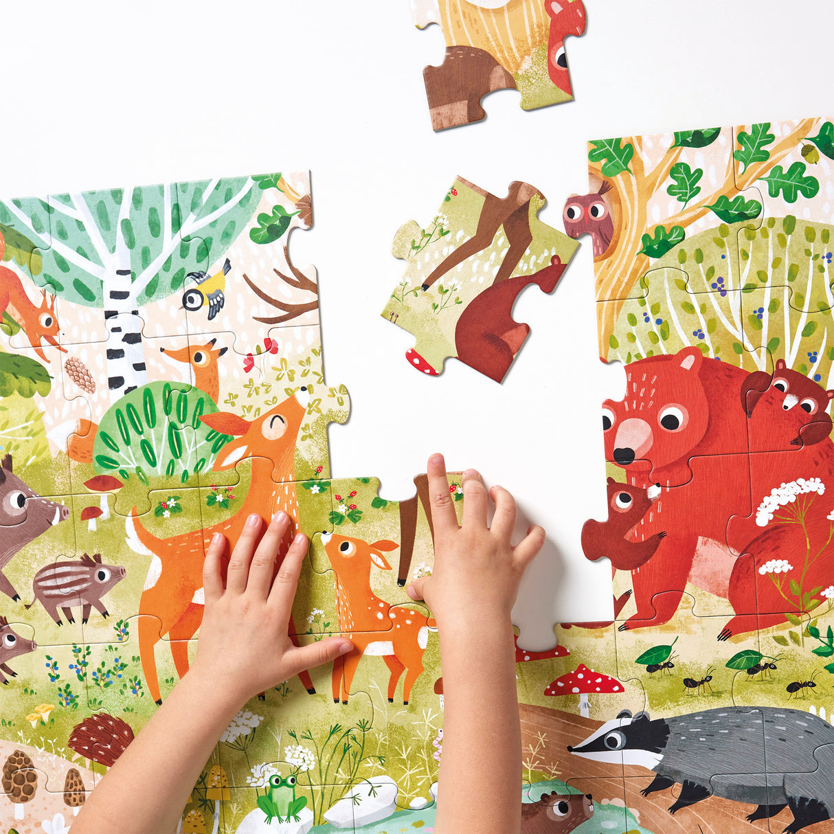 Child assembling colorful 40pc Forest Animals Wild Jumbo Puzzle with illustrated forest animals and plants.