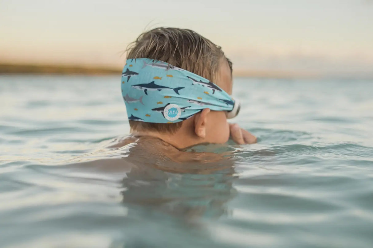 Child swimming wearing Googles Shark Attack with shark print strap and white frame swim goggles in water.