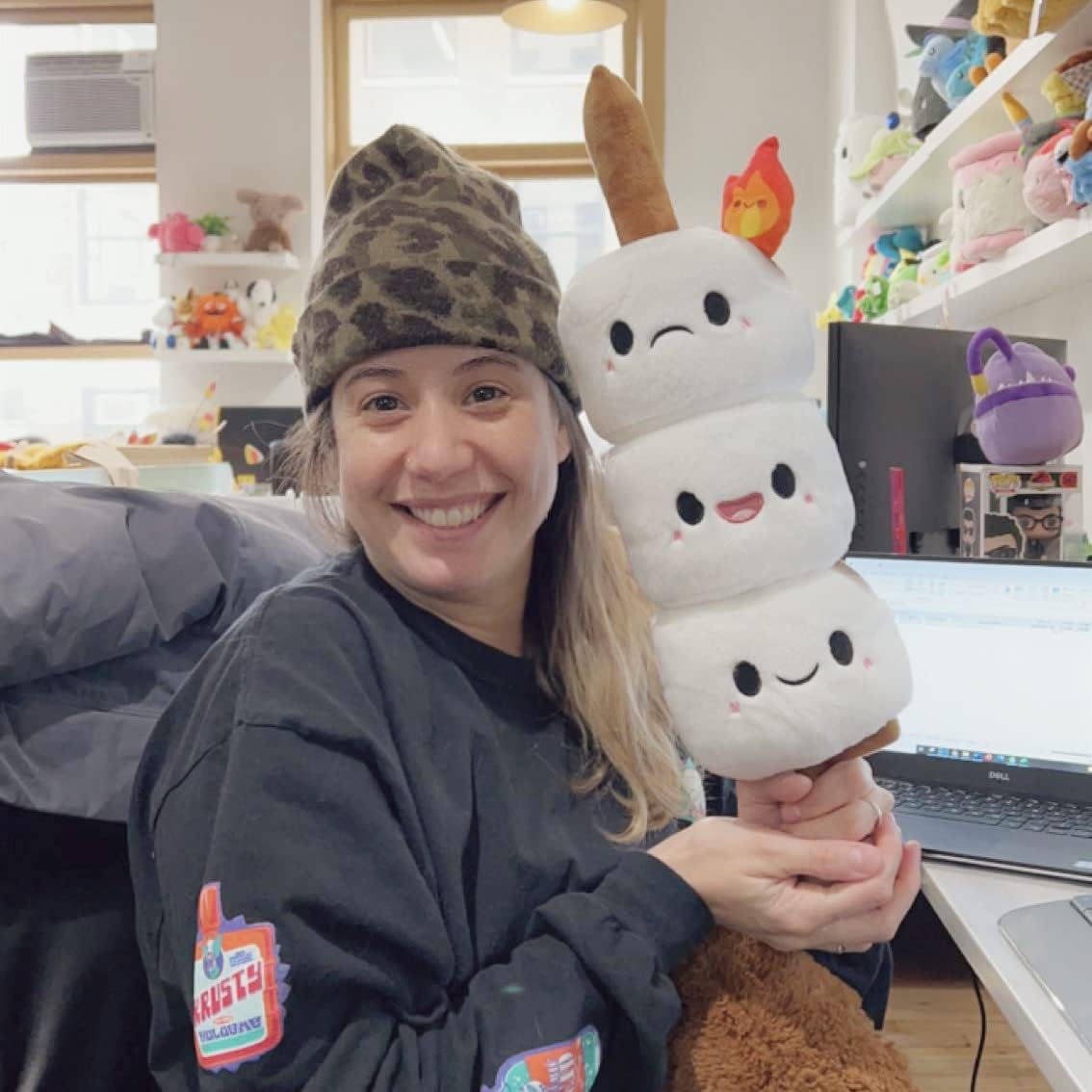 Person smiling and holding a Marshmallow Stick Mini plush toy with three stacked smiling marshmallows on a stick.