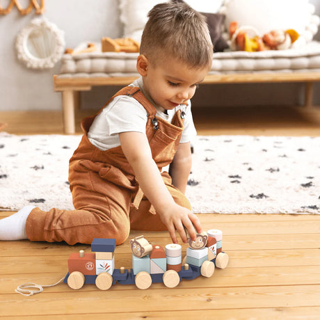 Toddler playing on wooden floor with colorful Ocean Stacking Train toy featuring ocean-themed blocks and shapes