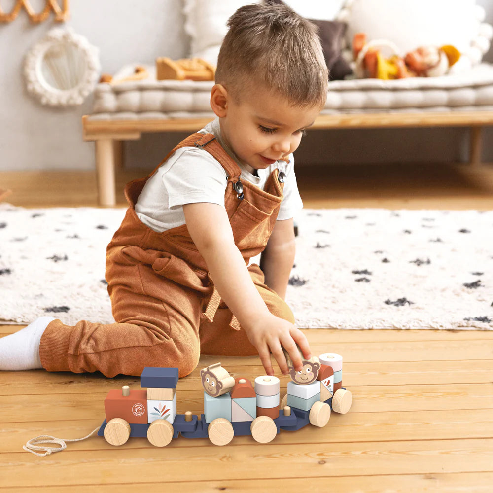 Toddler playing on wooden floor with colorful Ocean Stacking Train toy featuring ocean-themed blocks and shapes