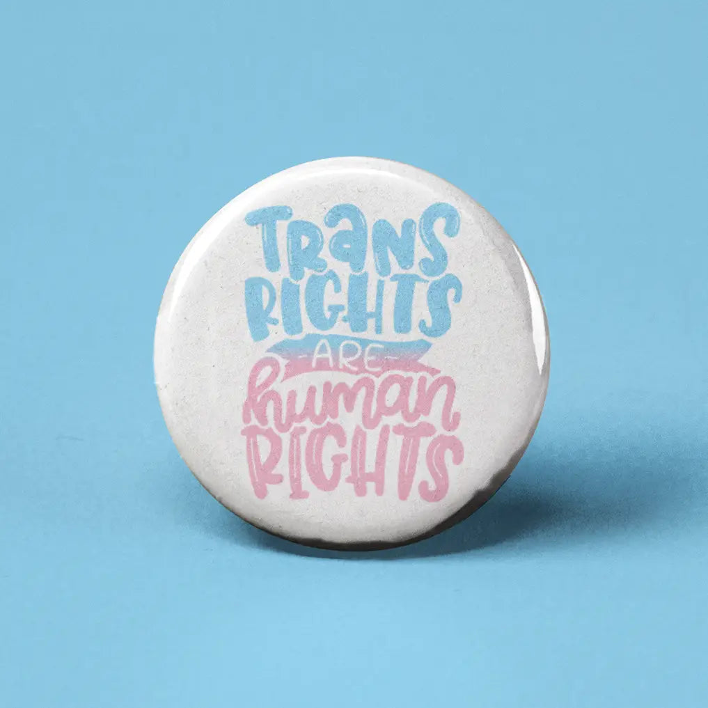 Button | Trans Rights Are Human Rights with blue and pink lettering on a white 1.25-inch round pin for self-expression