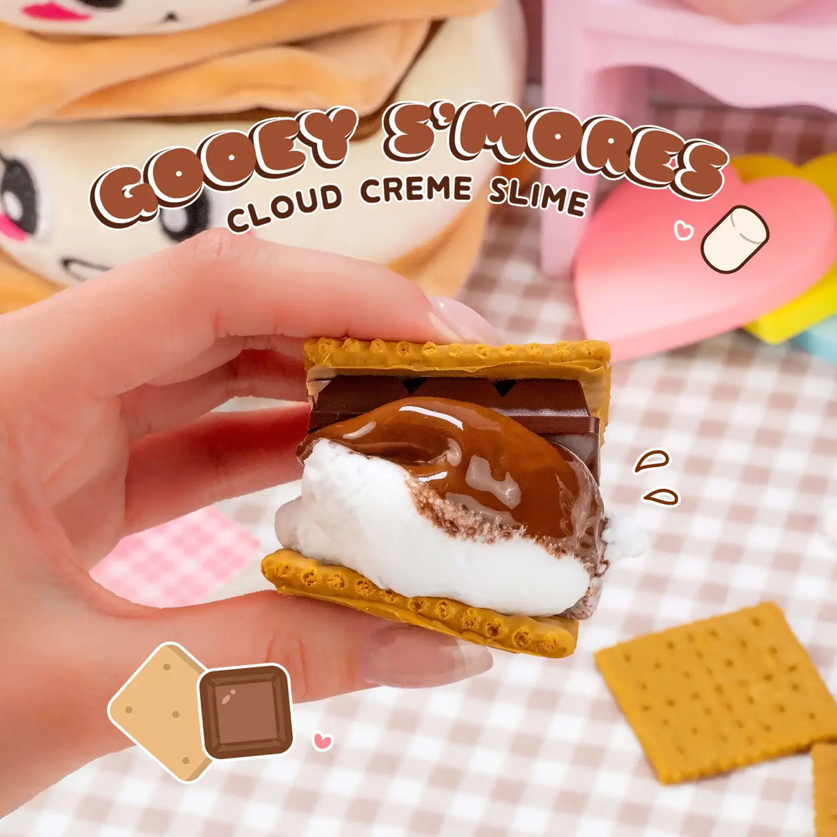 Hand holding Gooey S'mores Cloud Creme Slime with chocolate and marshmallow texture and realistic graham cracker charm.