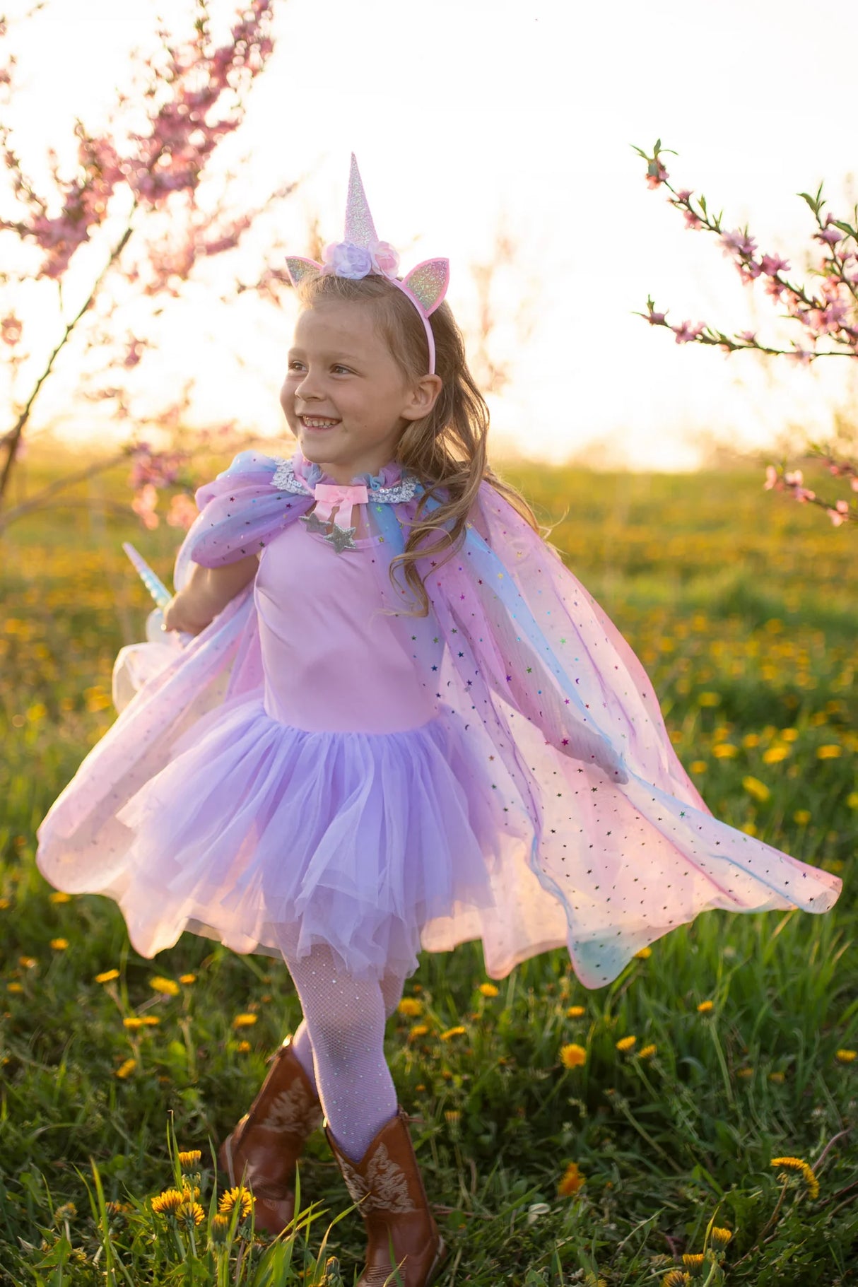 Young girl wearing the Rainbow Unicorn Cape & Headband set with pastel cape and sparkly unicorn headband outdoors.