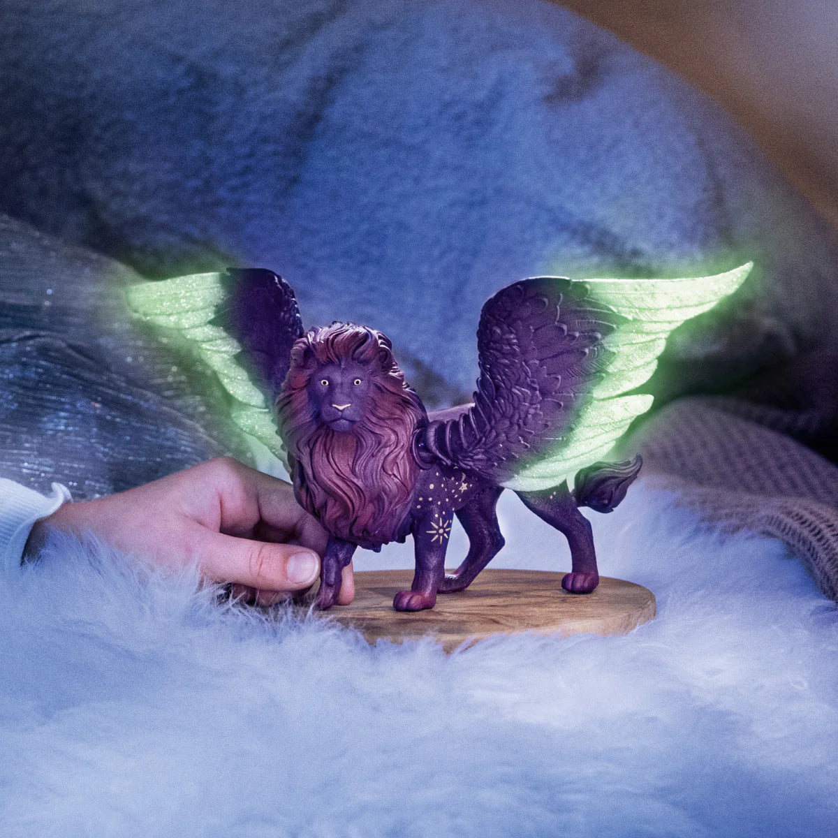 Bayala | Moon Lion figurine with glowing wings and starry dark fur held by a hand on a soft surface.