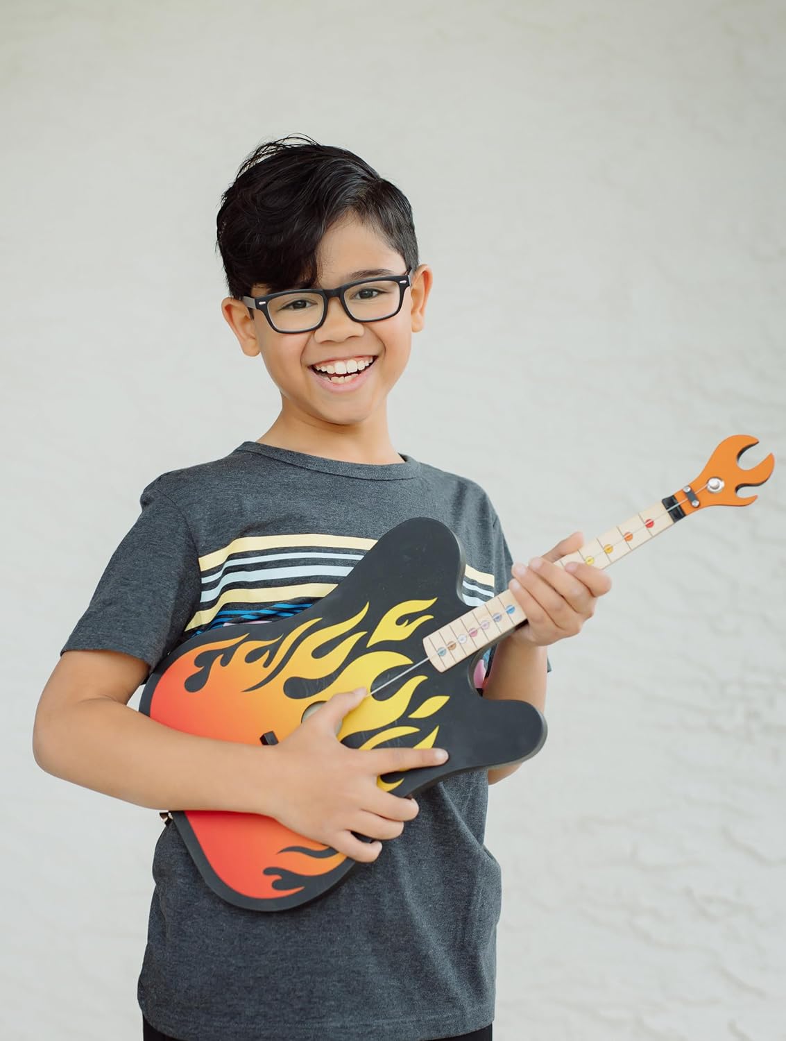Happy child playing the TinkerTar | Flames Electric 1-string guitar with flame design, perfect for young beginners.