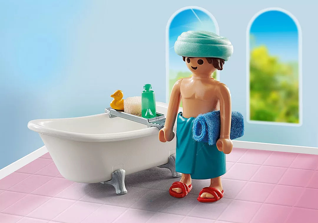 Special Plus | Man w/Bathtub toy figure with towel and slippers standing beside a white bathtub in a bright room.