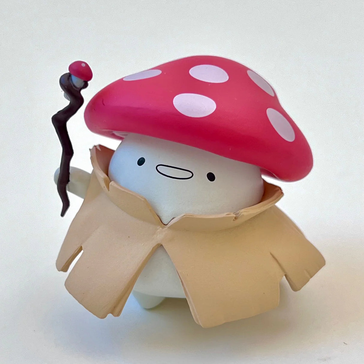 Mush Spirit Blind Box figure with red mushroom hat, beige cloak, and a staff, part of the collectible mystery series.
