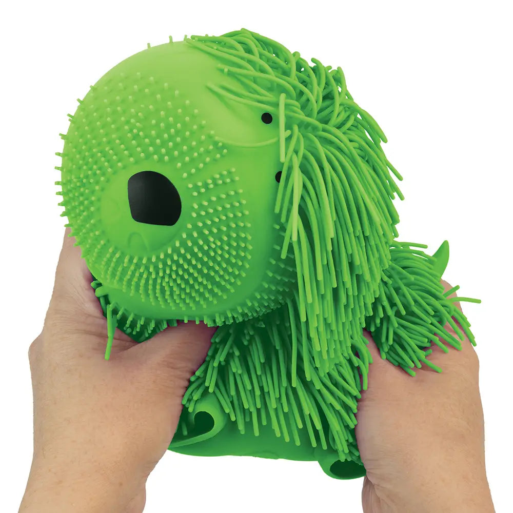 Hands squeezing a green, squishy, textured Wiggly Dog Mega toy with floppy furry details and playful design.