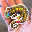 Hand holding a Spotted Salamander Holographic Sticker showing colorful spots and curled tail, durable and waterproof.