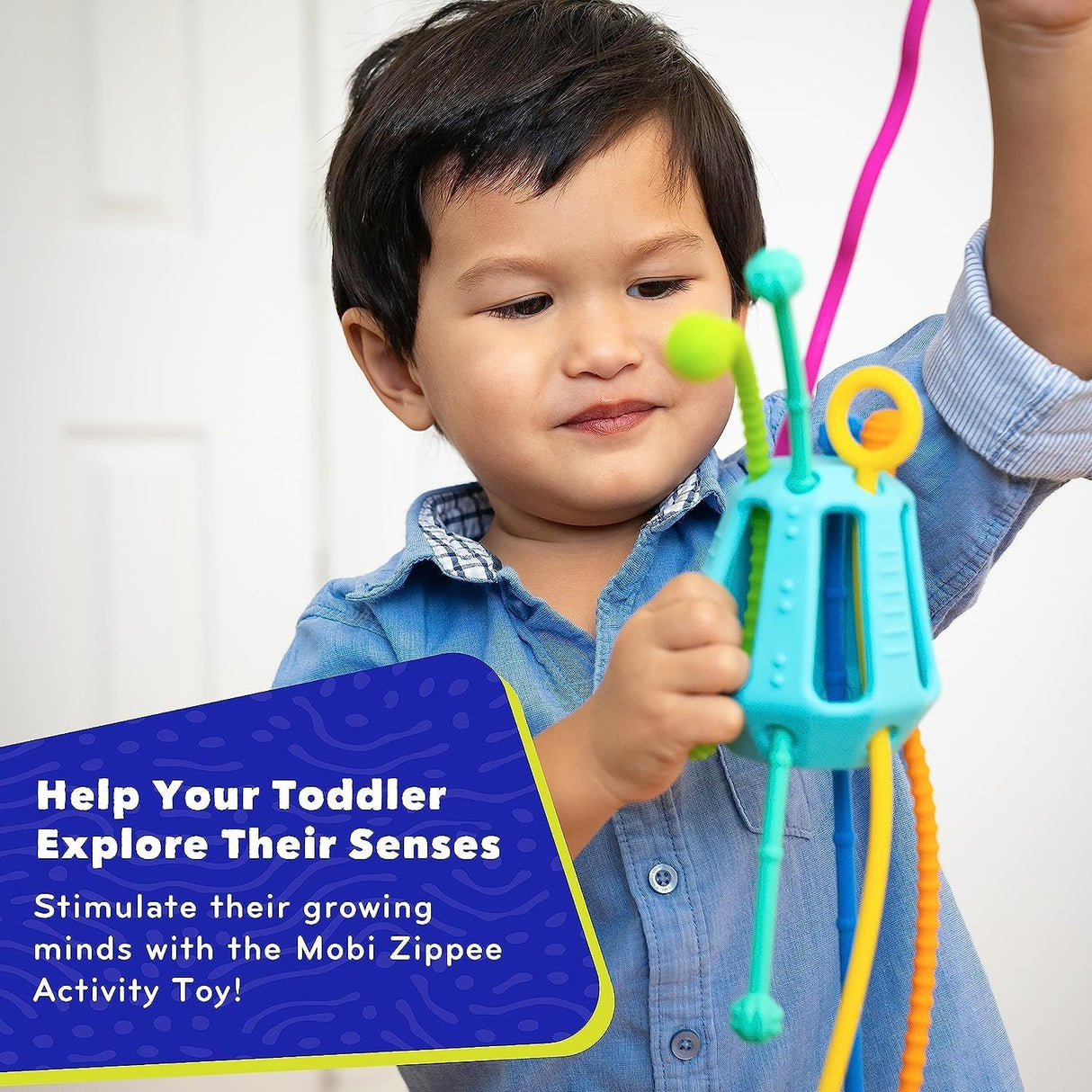Toddler playing with colorful Zippee Activity Toy featuring textured cords and soft silicone for sensory development.