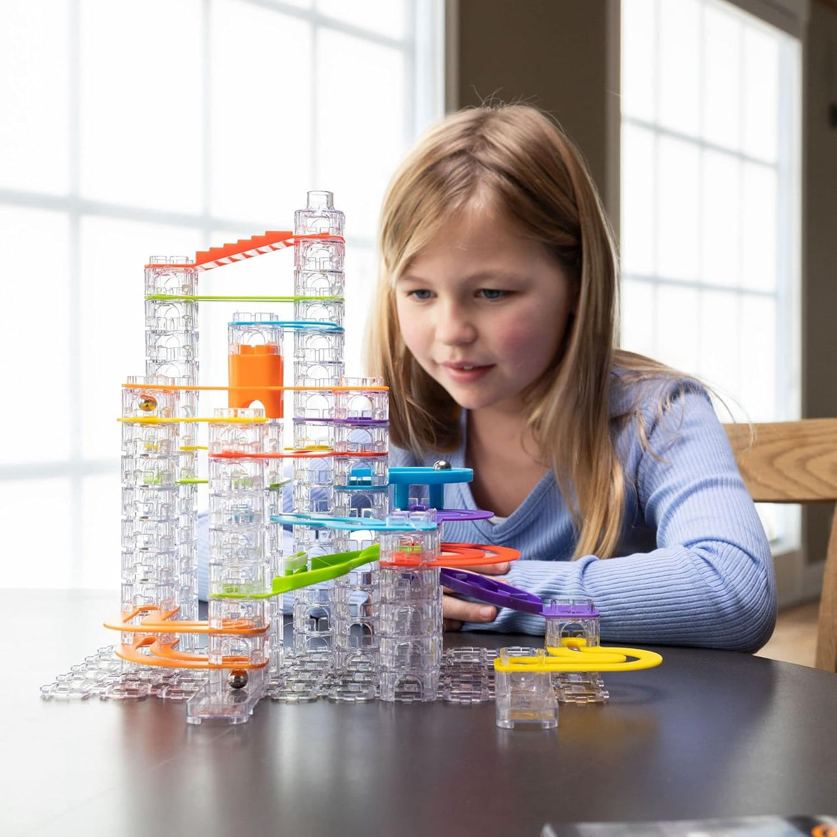 Child playing with colorful hollow stacking cubes and tracks in the Trestle Tracks Deluxe Set marble-run toy.