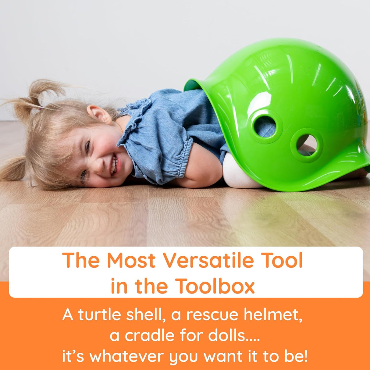 Child smiling while lying on floor partially covered by bright green Bilibo toy shaped like a turtle shell and helmet.